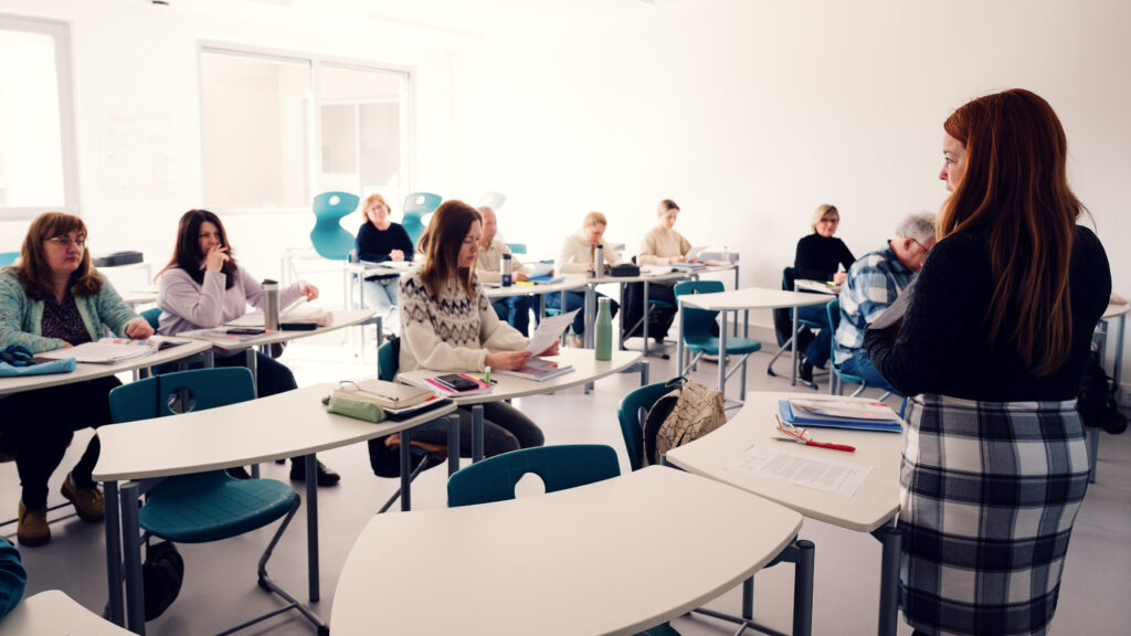 Trainerin im Schulungsraum der BPI Akademie, Teilnehmer:innen arbeiten an Einzeltischen mit Unterlagen