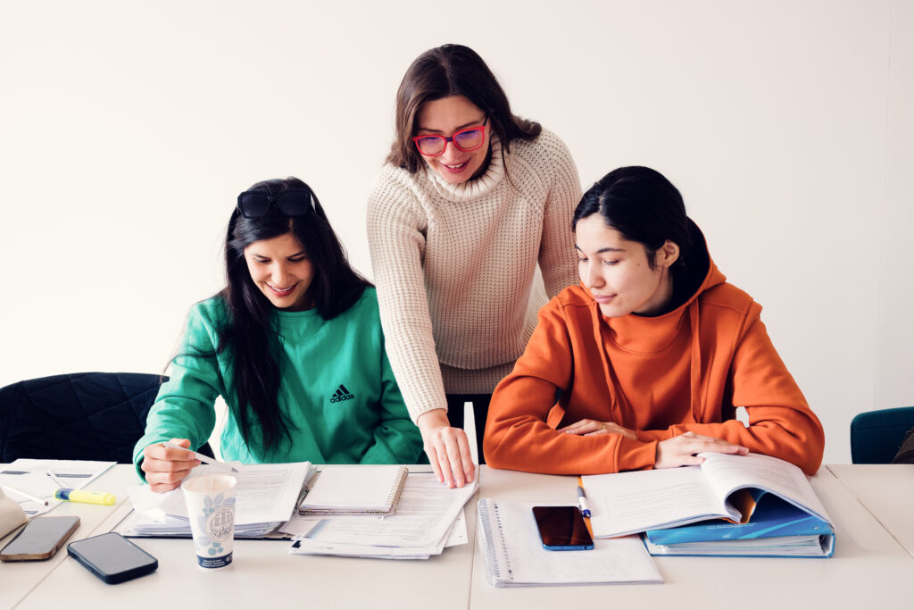 Trainerin erklärt zwei Teilnehmerinnen im Kursraum der BPI Akademie ihre Kursunterlagen.