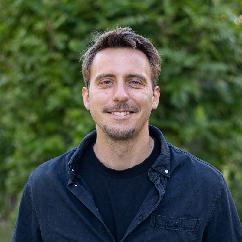 Porträt von Oliver Böck, Bereichsleiter Bildung und Integration der ÖJAB, vor einer begrünten Wand