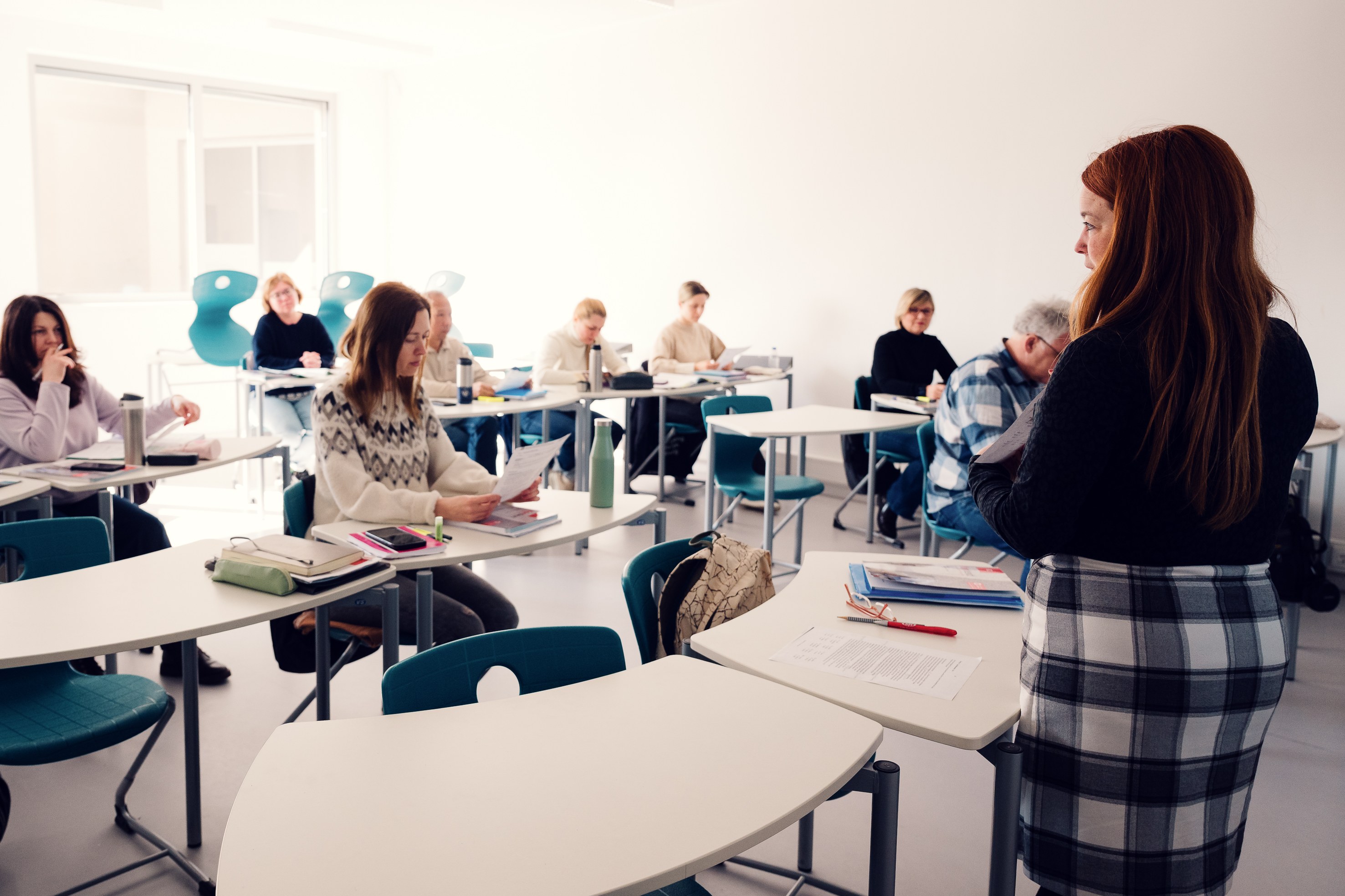 Trainerin im Schulungsraum der BPI Akademie, Teilnehmer:innen arbeiten an Einzeltischen mit Unterlagen